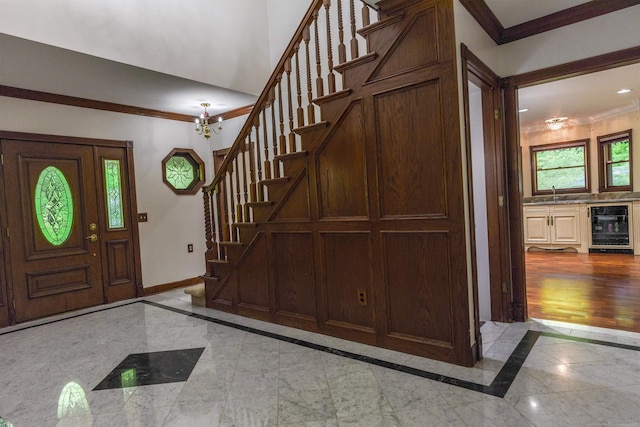 tiled entryway featuring sink, beverage cooler, and crown molding