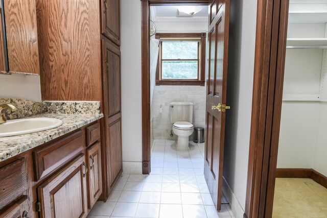 bathroom with ornamental molding, tile floors, tile walls, vanity, and toilet