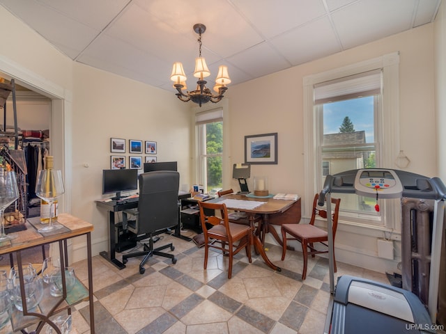 office space with a drop ceiling and a notable chandelier