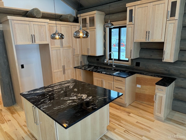 kitchen with light brown cabinets, rustic walls, a sink, and light wood-style flooring