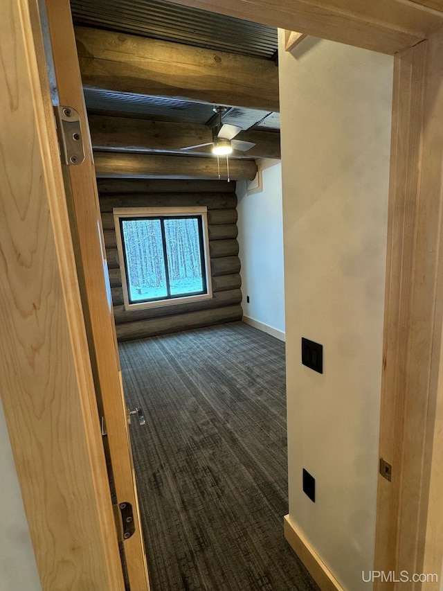 spare room with ceiling fan, dark wood-type flooring, baseboards, log walls, and beamed ceiling