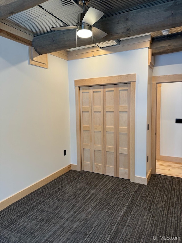 basement featuring dark colored carpet and ceiling fan