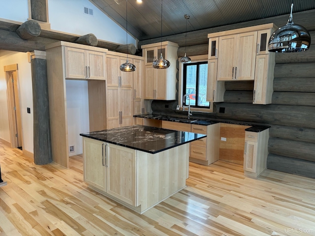 kitchen with light wood finished floors, rustic walls, visible vents, a sink, and high vaulted ceiling