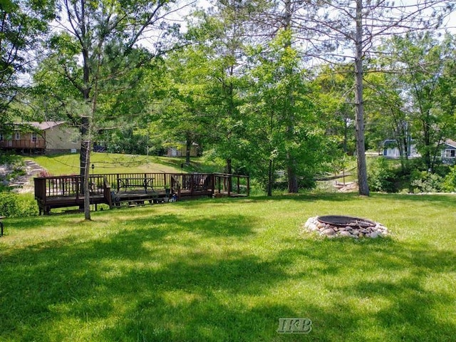 view of property's community with a lawn, a deck, and an outdoor fire pit