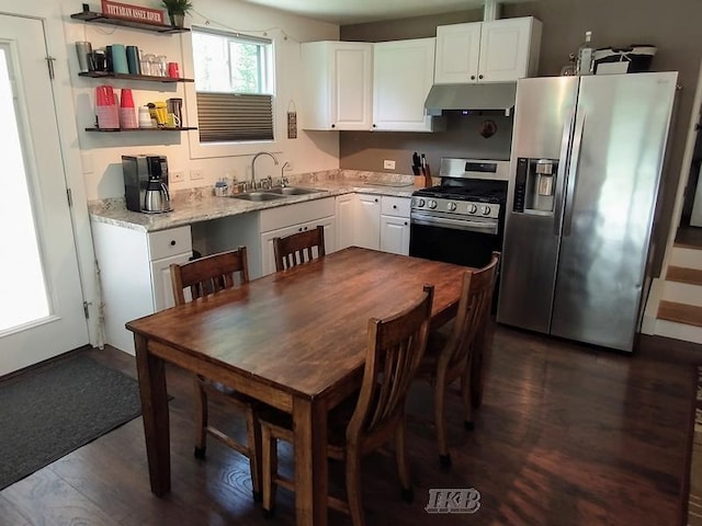 kitchen with appliances with stainless steel finishes, light stone counters, sink, white cabinets, and dark hardwood / wood-style floors