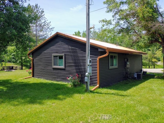 view of side of property featuring central air condition unit and a lawn