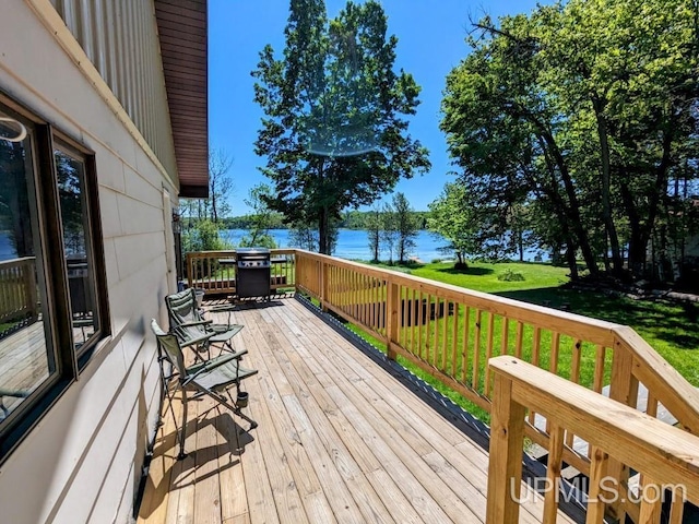 deck with a water view, a yard, and grilling area