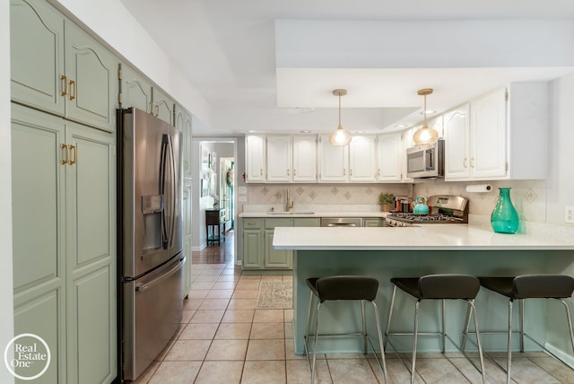 kitchen featuring kitchen peninsula, backsplash, stainless steel appliances, sink, and white cabinetry