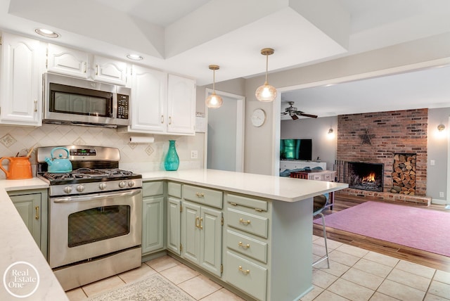 kitchen with pendant lighting, white cabinets, appliances with stainless steel finishes, light hardwood / wood-style floors, and kitchen peninsula