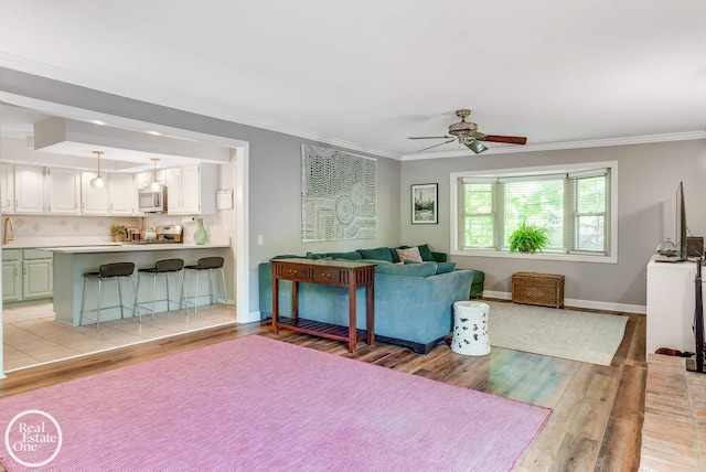 living room with ceiling fan, light hardwood / wood-style floors, and ornamental molding