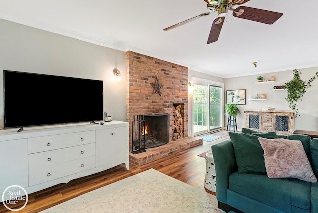 living room featuring hardwood / wood-style flooring, ceiling fan, ornamental molding, and a brick fireplace