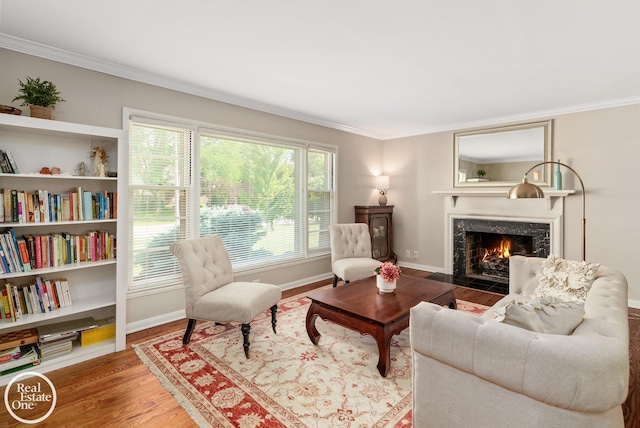 sitting room featuring a high end fireplace, wood-type flooring, and ornamental molding