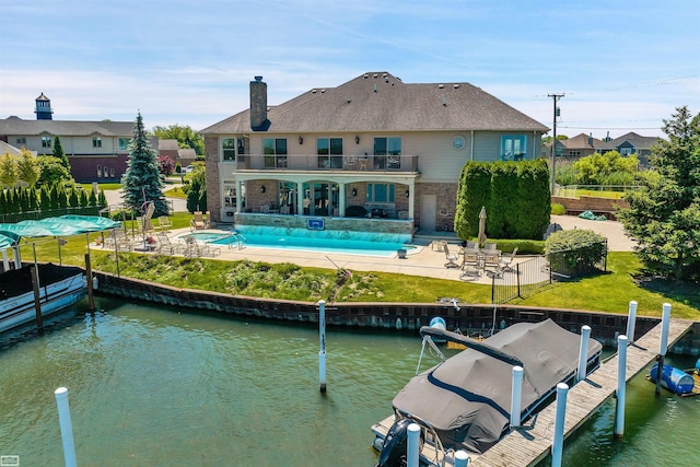 back of property with a fenced in pool, a patio area, a balcony, and a water view