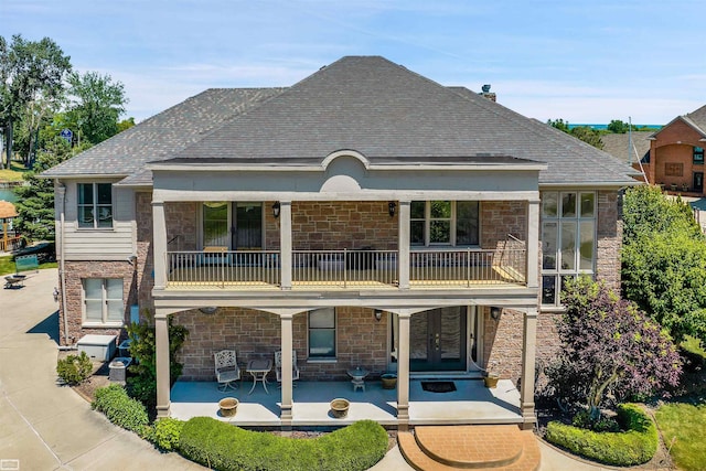 rear view of property featuring a patio area, a balcony, and french doors