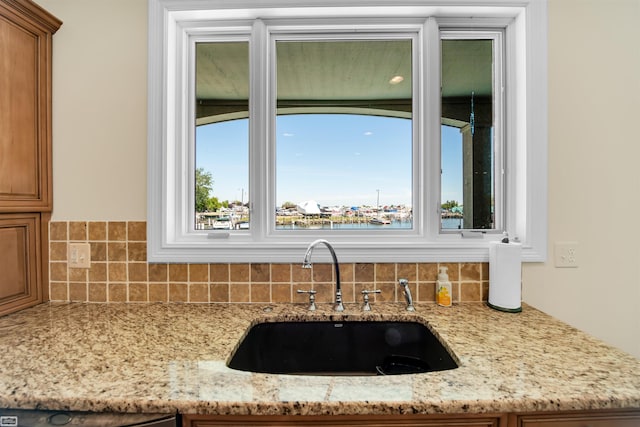 room details with decorative backsplash, light stone counters, and sink