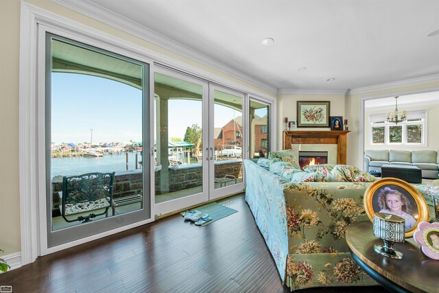 living room with french doors, an inviting chandelier, dark hardwood / wood-style flooring, crown molding, and a water view