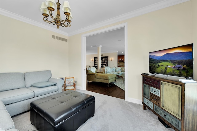 living room with ornate columns, crown molding, a chandelier, and light wood-type flooring