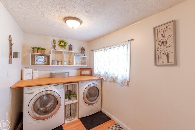 laundry area with light hardwood / wood-style flooring, washer and dryer, and a textured ceiling