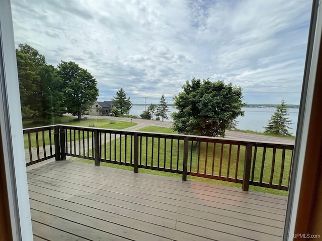 wooden terrace with a water view and a lawn