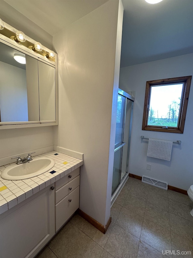 bathroom with a shower with door, vanity, and tile patterned flooring