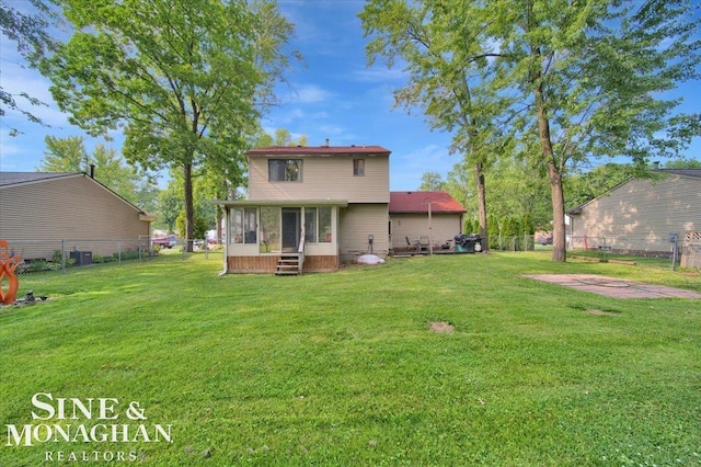 rear view of house featuring a lawn and a sunroom