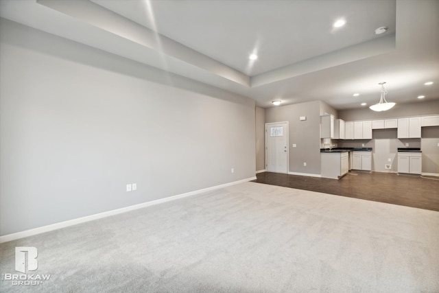 unfurnished living room with a raised ceiling and carpet floors