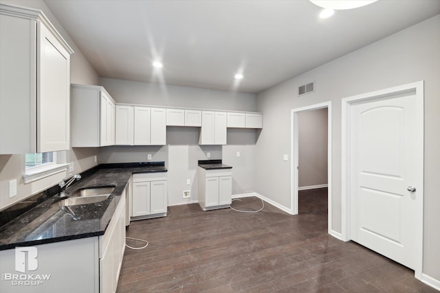 kitchen featuring white cabinets, sink, dark stone counters, and dark wood-type flooring