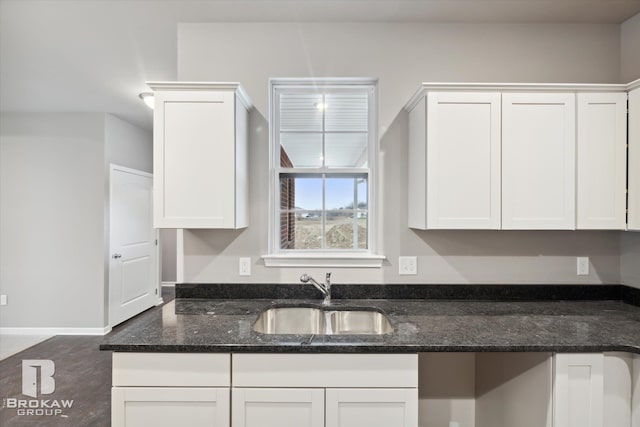 kitchen featuring white cabinetry, dark stone counters, and sink