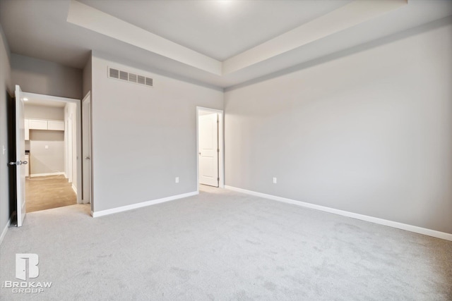 unfurnished bedroom with a tray ceiling and light carpet