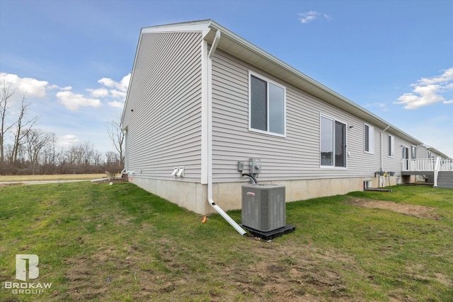 view of side of home featuring a yard and central AC unit