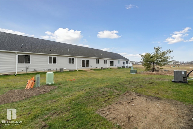 rear view of property featuring cooling unit and a yard