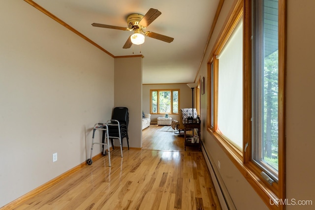 interior space with ornamental molding, ceiling fan, and light wood-type flooring