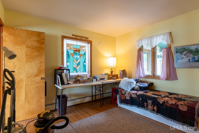 bedroom featuring hardwood / wood-style floors and a baseboard heating unit