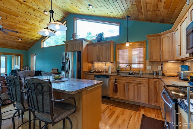 kitchen featuring sink, stainless steel appliances, backsplash, and hanging light fixtures