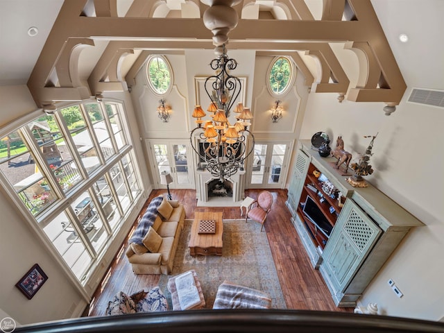 living room with an inviting chandelier, hardwood / wood-style floors, high vaulted ceiling, and french doors