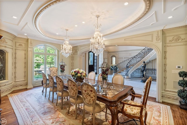 dining space with hardwood / wood-style floors, a tray ceiling, ornamental molding, and a chandelier