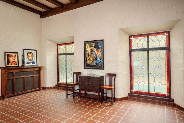 living area featuring beamed ceiling and tile patterned floors