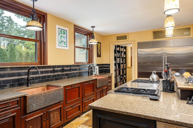 kitchen featuring built in fridge, decorative backsplash, sink, and decorative light fixtures