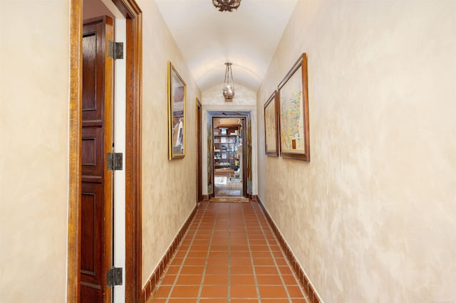 hall featuring brick ceiling, dark tile patterned floors, and vaulted ceiling