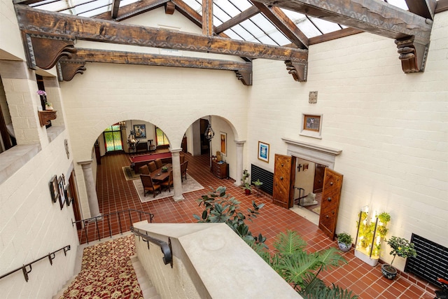 living room featuring beamed ceiling, high vaulted ceiling, and brick wall