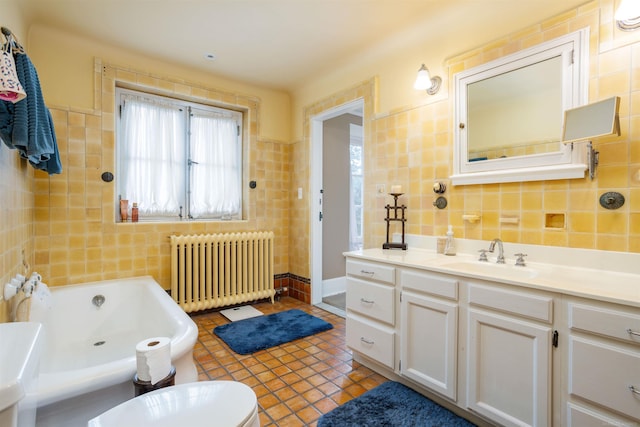 bathroom featuring radiator heating unit, a tub to relax in, toilet, vanity, and tile walls