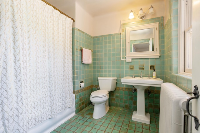 bathroom with toilet, tile patterned floors, radiator, and tile walls