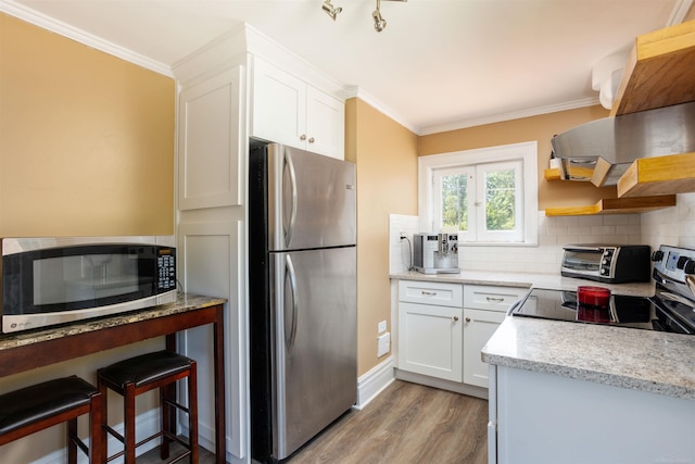 kitchen with tasteful backsplash, appliances with stainless steel finishes, crown molding, white cabinets, and light wood-type flooring