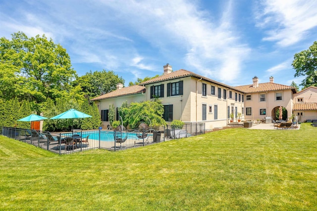 back of property featuring a lawn, a patio area, and a fenced in pool