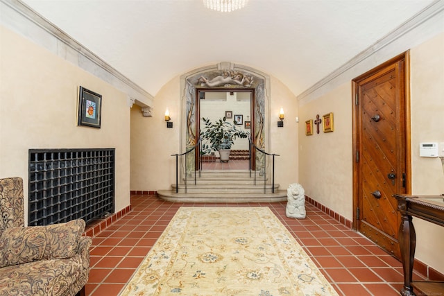 corridor with ornamental molding, dark tile patterned flooring, and lofted ceiling