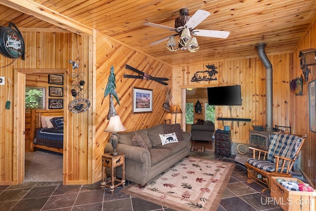 living room featuring a wood stove, wooden walls, plenty of natural light, and wood ceiling