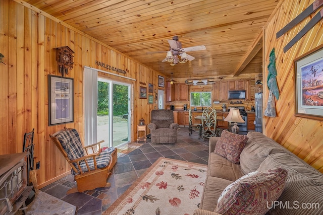 living room featuring ceiling fan, wood walls, and wooden ceiling