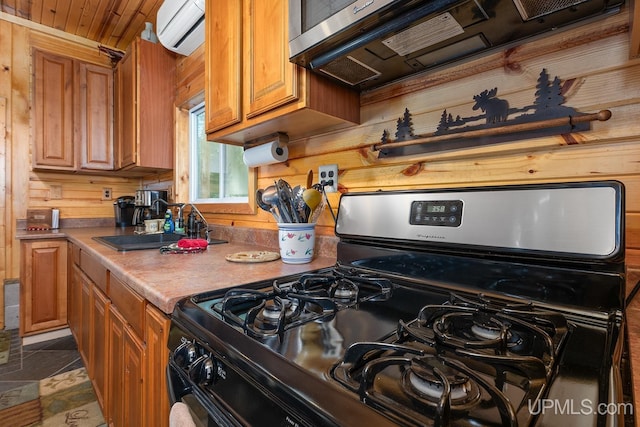 kitchen with black gas range, wooden walls, sink, and an AC wall unit