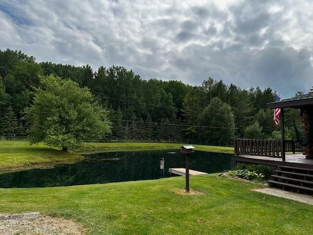 surrounding community featuring a deck with water view and a lawn