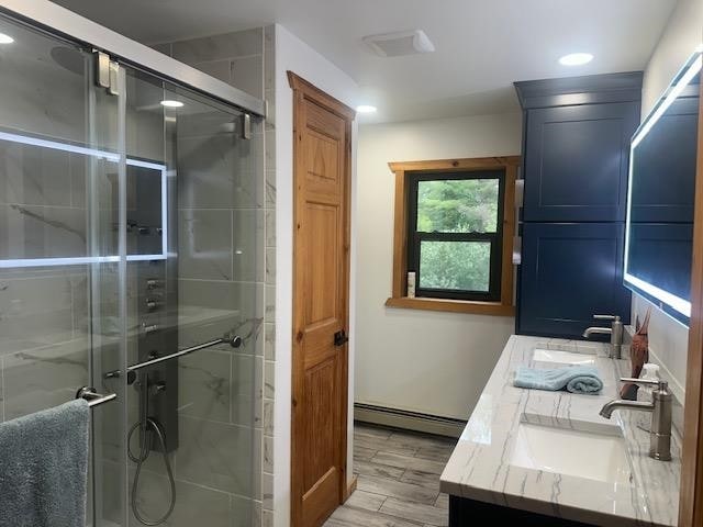 bathroom featuring double vanity, a baseboard heating unit, a shower with shower door, and hardwood / wood-style floors